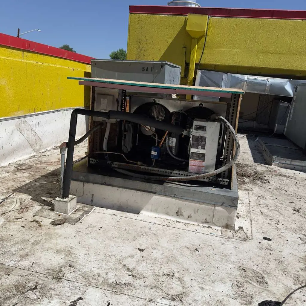 Refrigeration condensing unit on a rooftop beside a yellow building